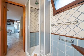 A shower with a glass door, a wooden frame, and a towel rack.