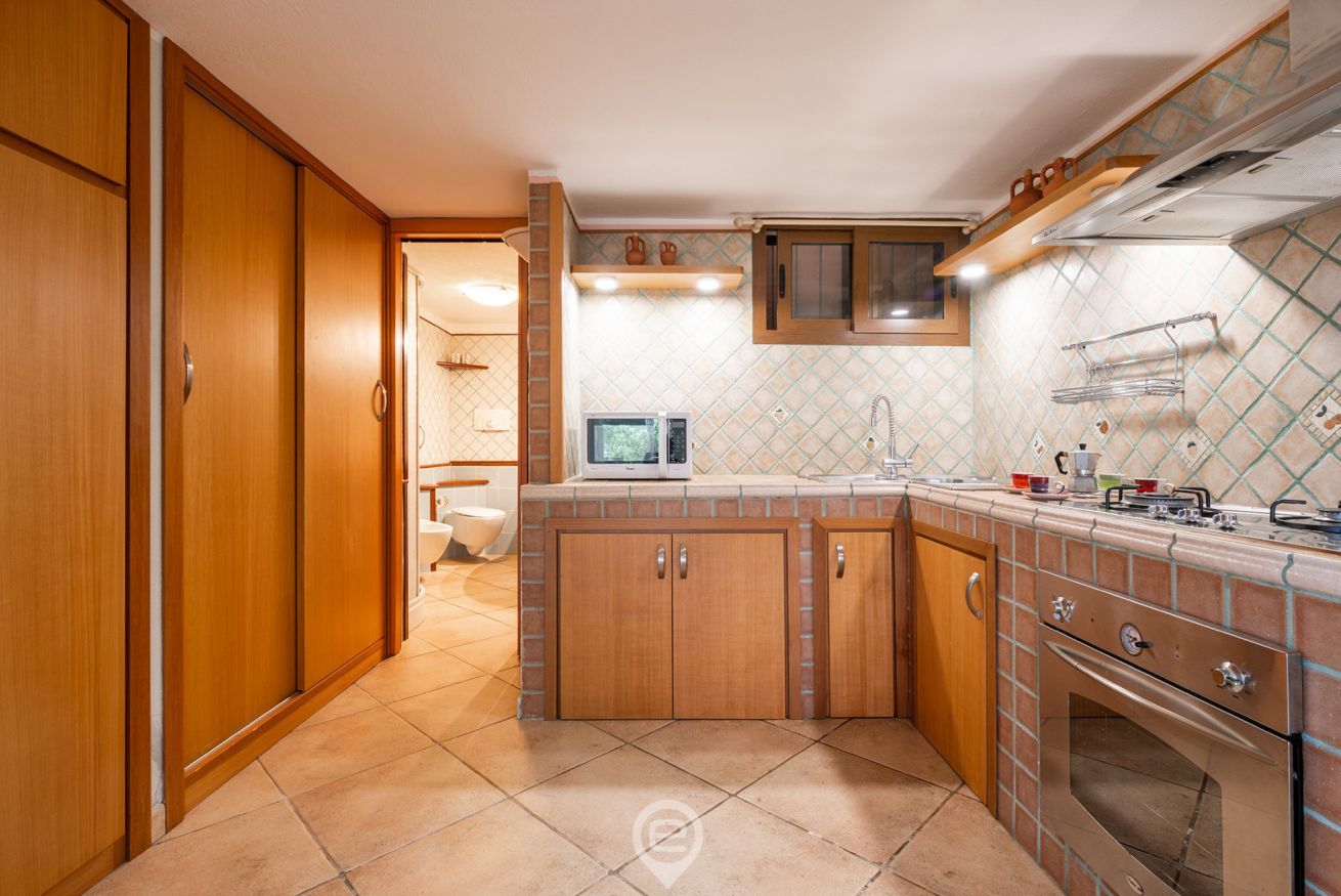 Una cocina con armarios de madera, microondas, fregadero y estufa.
