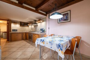 A kitchen with wooden cabinets, a dining table with chairs, and a hanging light fixture.
