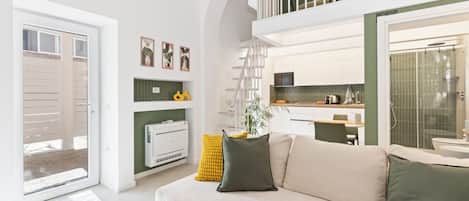 Un salon moderne avec un canapé, un escalier et un coin cuisine.