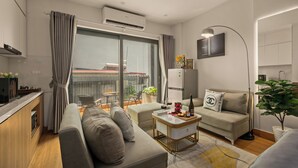 A modern living room with a sofa, a coffee table, a TV, and a balcony with a view. - The West Lake Serenity'N Homestay Ha Noi (Hanoi)
