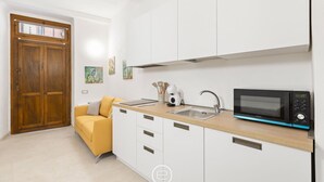 Una cocina compacta con armarios blancos, una encimera de madera, un microondas y un lavabo.