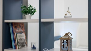 Una estantería con libros, una planta en maceta, un vaso y un farol.