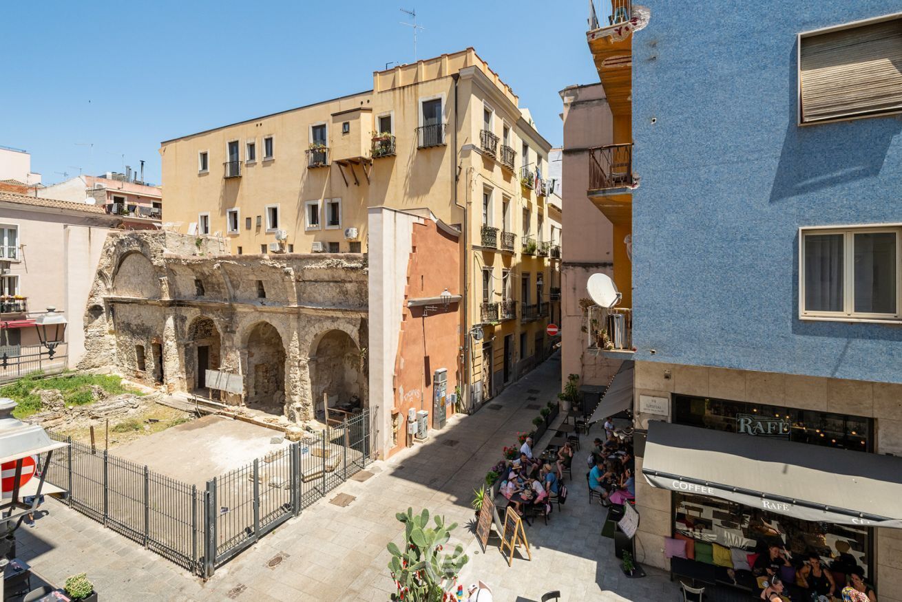 A street with a café and outdoor seating, historic buildings, and a clear sky.