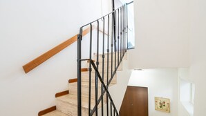 Una scala con gradini in legno e un corrimano in metallo, che conduce a una stanza con una porta in legno e un quadro appeso al muro.