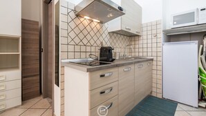 Una cucina compatta con piano cottura integrato, macchina per il caffè e forno a microonde.