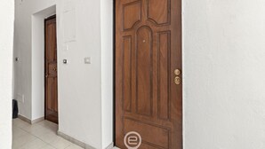 Um corredor com duas portas de madeira, uma delas com fechadura visível e um interruptor de luz na parede.