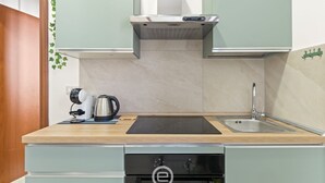 Cozinha compacta com forno embutido, pia e máquina de café no balcão.