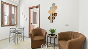 Uma sala de estar moderna com duas poltronas marrons, uma mesa redonda pequena com uma planta e uma decoração de parede hexagonal.
