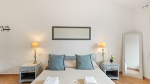 A bedroom with a bed, two bedside tables with lamps, a mirror, and a door.