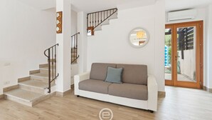 A spacious living area with a staircase, a round mirror, and a white sofa.