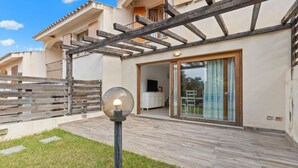 A modern villa with a wooden deck, a glass door entrance, and a visible kitchen area. - Garden Delight House (Chia)