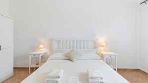 A neatly arranged hotel room with a large bed, two bedside tables with lamps, and a white headboard. - Garden Delight House (Chia)