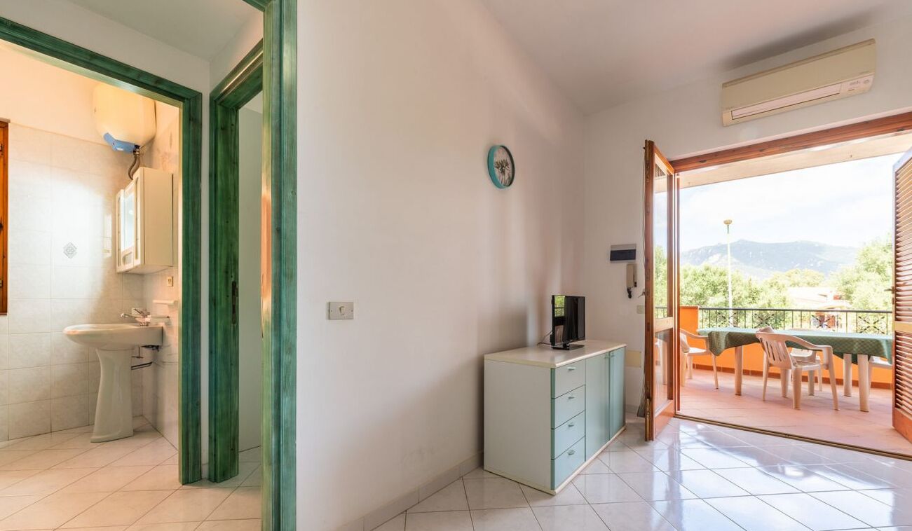 Una habitación con baño, un pequeño kitchenette y un balcón con mesa y sillas.
