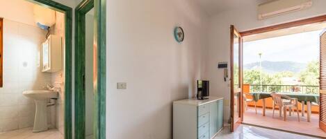 Una habitación con baño, un pequeño kitchenette y un balcón con mesa y sillas.