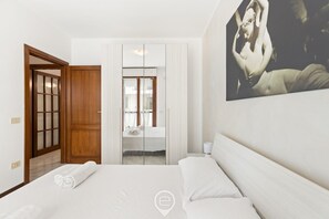Ein Hotelzimmer mit einem Bett, einer Holztür, einem Spiegel und einem Bild an der Wand.
