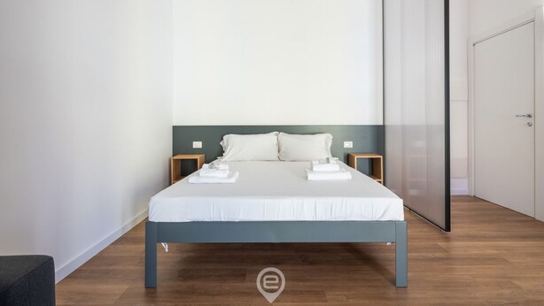 Ein modernes Schlafzimmer mit einem Bett, Holznachttischen und einem grauen Kopfseitenverkleidung.