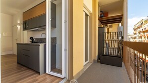 Eine moderne Küche mit Einbauofen, Mikrowelle und Spüle. Eine Schiebetür aus Glas führt auf einen Balkon mit Geländer.