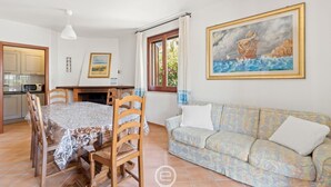 Zona pranzo con tavolo e sedie, un divano e un quadro appeso al muro.