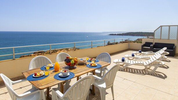 A terrace with a table set for breakfast, overlooking the sea. - Penthouse San Lorenzo (Portimão)