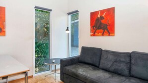 Un soggiorno moderno con un divano grigio, un tavolino rotondo e una finestra vista verde.