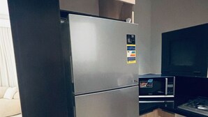 A compact kitchen with a stainless steel refrigerator, a microwave, and a gas stove. - Apartment 2 in Zed Towers (El Sheikh Zayed City)
