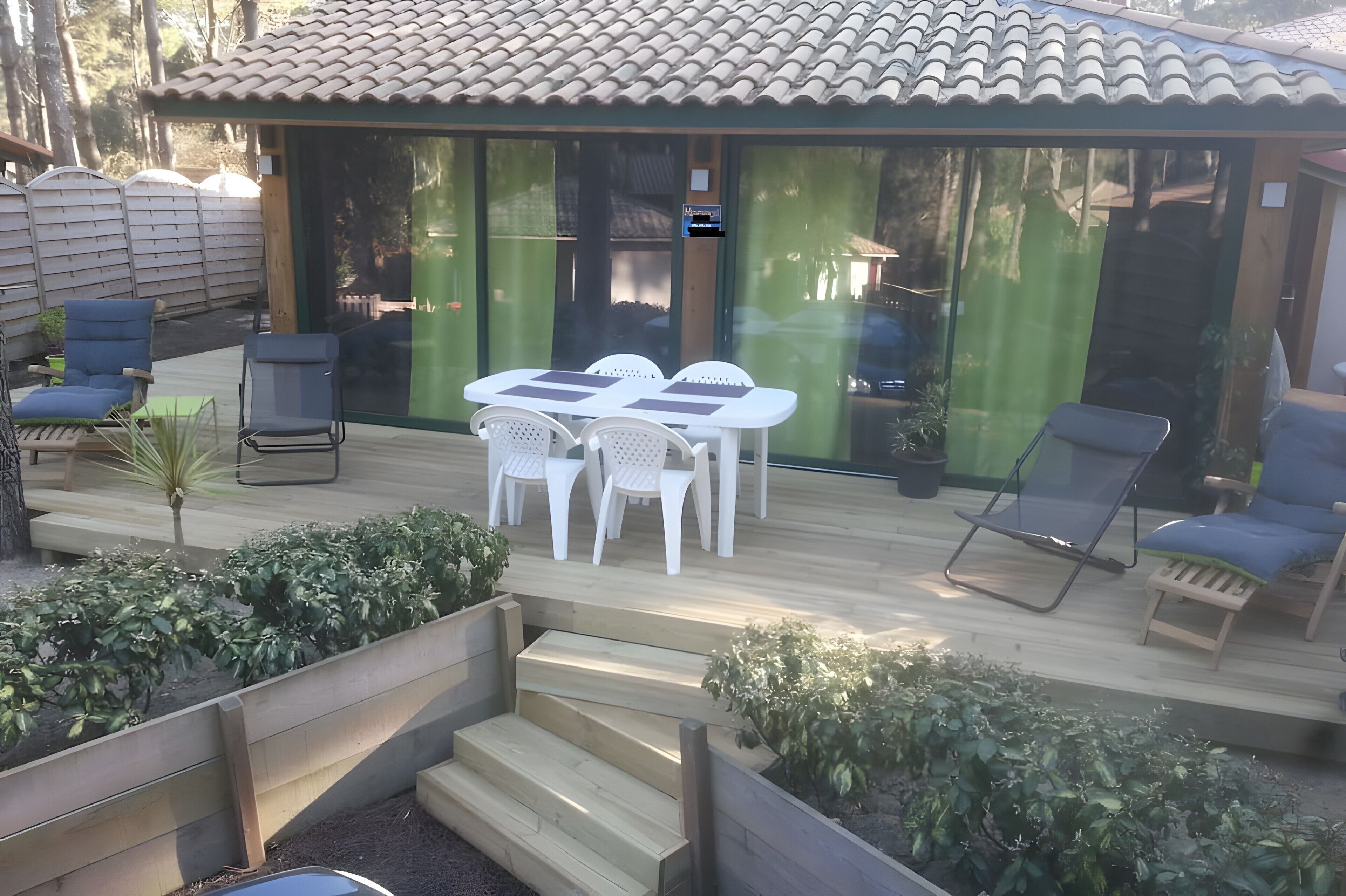 Eine Terrasse mit Tisch und Stühlen, eine kleine Treppe und ein Holzboden.