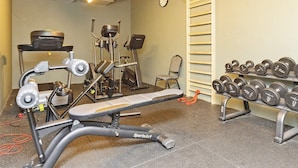 A gym with exercise equipment, a bench, dumbbells, and a clock on the wall. - 4 Person Holiday Park Home in Gilleleje (Gilleleje)