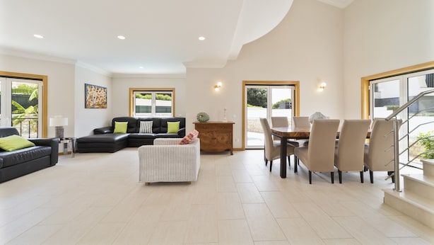 A spacious living area with a black sofa, a white wicker ottoman, and a dining table with chairs. - Villa Gale Coast in Gal (Albufeira)