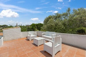 An outdoor patio with white wicker furniture, including a sofa and two chairs, on a tiled surface. - Villa Panta Rei - Liscia di Vacca (Liscia di Vacca)