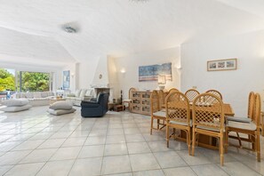 A spacious living area with a large window, a dining set, and a sofa. - Villa Panta Rei - Liscia di Vacca (Liscia di Vacca)