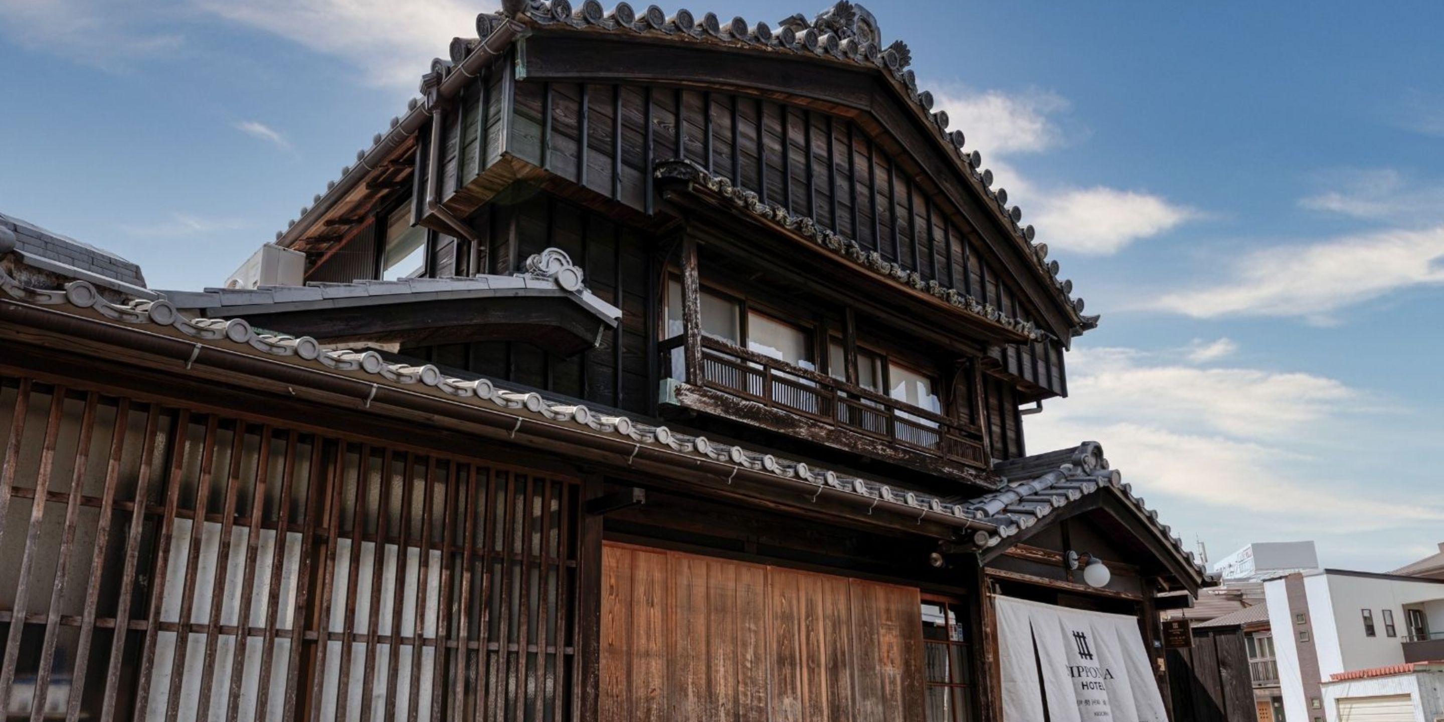 A traditional Japanese building with a wooden facade, a curved roof, and a wooden balcony.