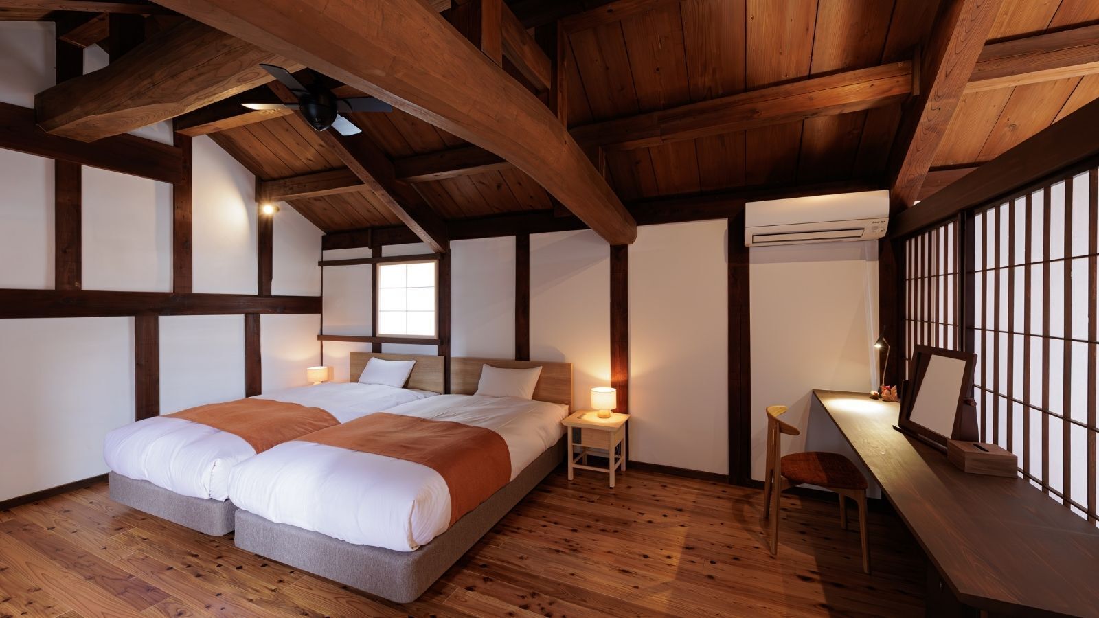 A bedroom with a large bed, bedside tables, a desk, and a window.