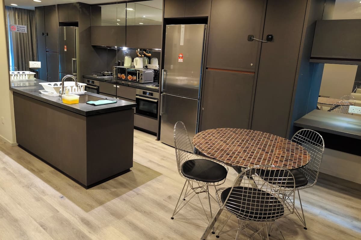 Una cocina moderna con una isla central, electrodomésticos de acero inoxidable y una zona de comedor con sillas de metal.