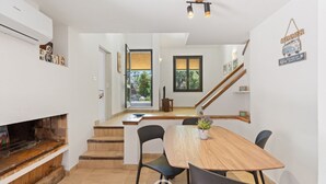 A modern kitchen with a wooden table and chairs, a built-in grill, and a staircase leading to a balcony.