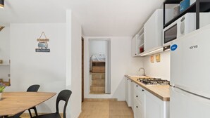 A compact kitchen with a gas stove, white cabinets, and a dining area with a wooden table and chairs.