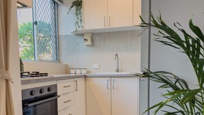 A modern kitchen with white cabinets, a stainless steel refrigerator, and a wooden floor.