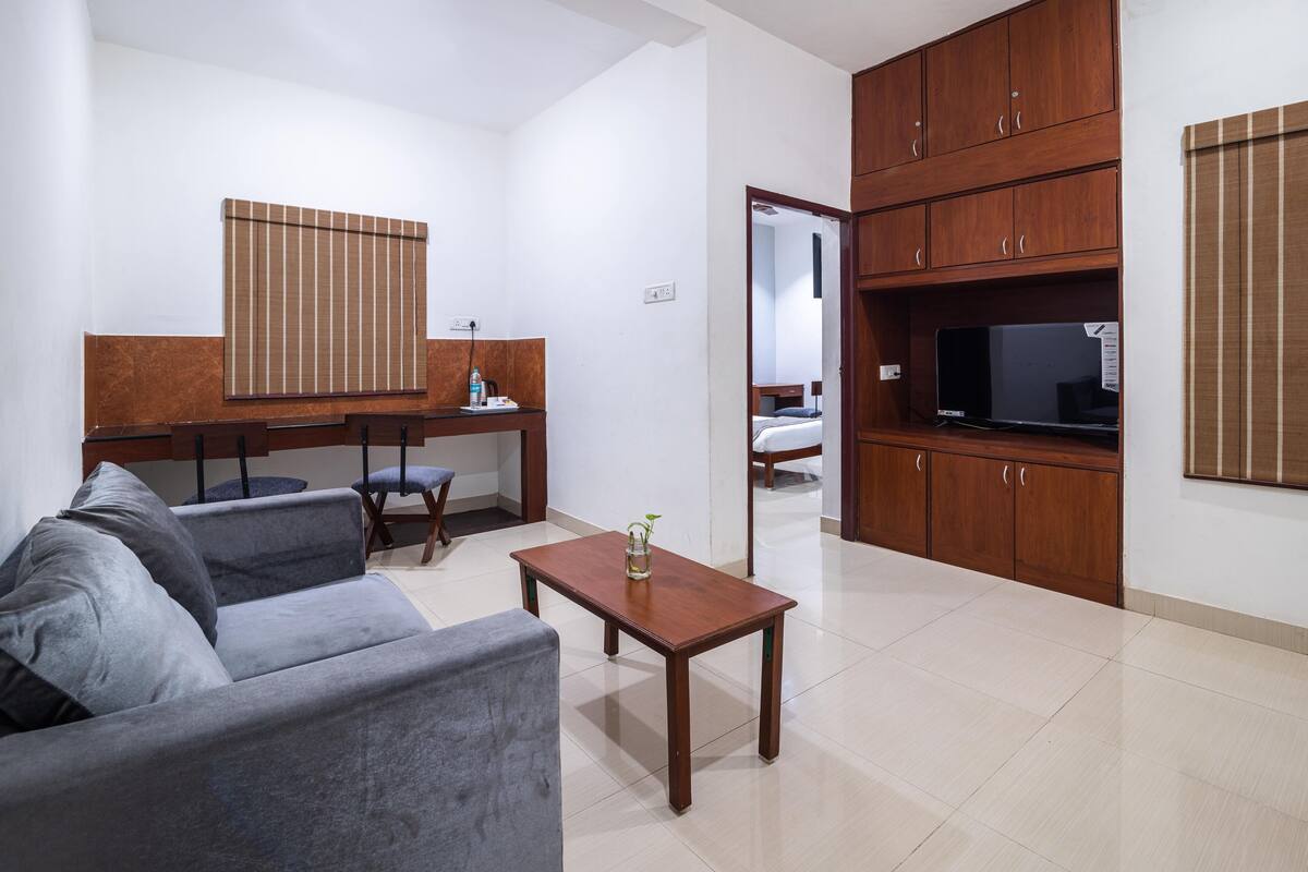 A living room with a sofa, a coffee table, a TV, and wooden cabinets.