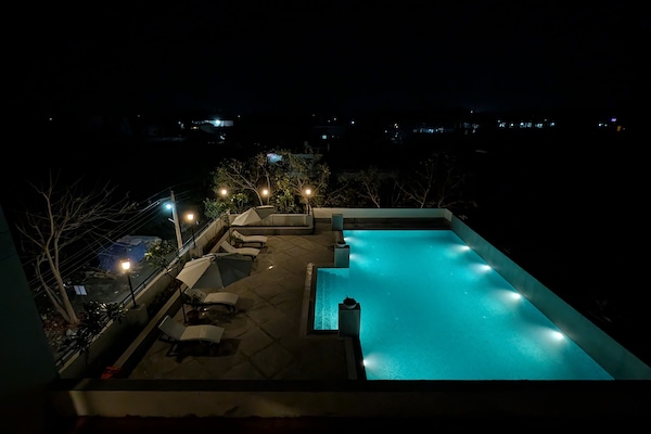 Una piscina al aire libre, sombrillas, sillones reclinables de piscina
