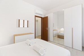 Ein modernes Hotelzimmer mit einem großen Bett, einem Holzkopfteil, einem Kleiderschrank und einem Spiegel.