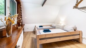 Ein Schlafzimmer mit einem hölzernen Bett, Nachttischen, einer Fensterbank und einer hängenden Leuchte.
