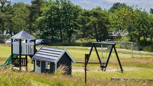 Een speelplaats met een glijbaan, schommel en een klein speelhuisje.