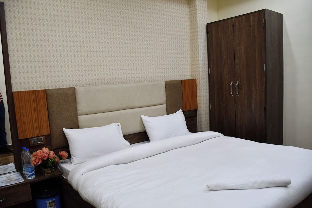 A hotel room with a large bed, wooden headboard, and a wardrobe.