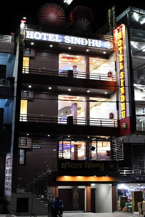 A multi-story hotel with a reception area on the ground floor, balconies on the upper floors, and a sign indicating a "ROUND FLOOR" and "RECEPTION" area. - Hotel Sindhu (Bareilly)