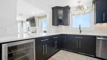 A modern kitchen with dark cabinetry, a stainless steel dishwasher, and a built-in wine cooler.
