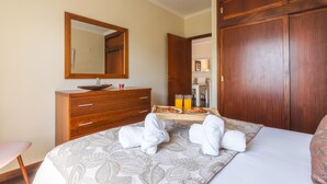 Una camera d'albergo con un letto, una cassettiera in legno, uno specchio e un armadio in legno.