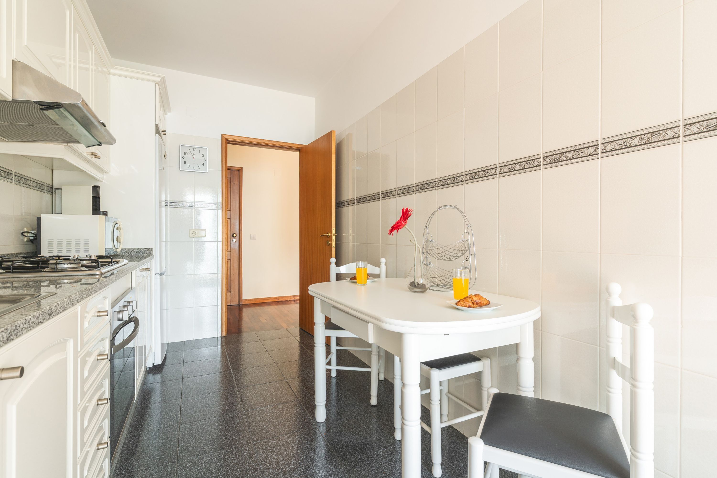 A kitchen with a dining table, chairs, a stove, and a refrigerator.
