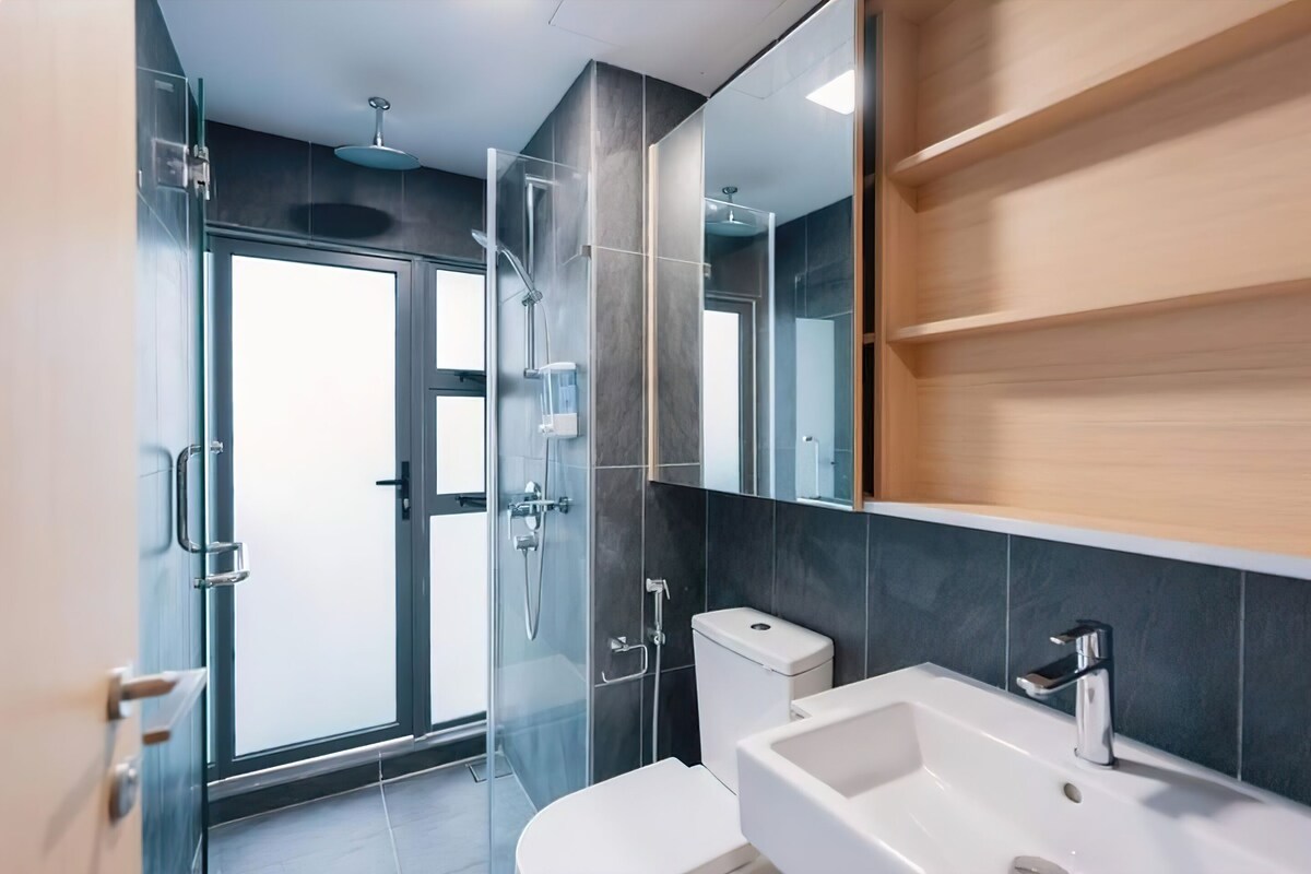 Un baño moderno con cabina de ducha de vidrio, un lavabo blanco y un inodoro.
