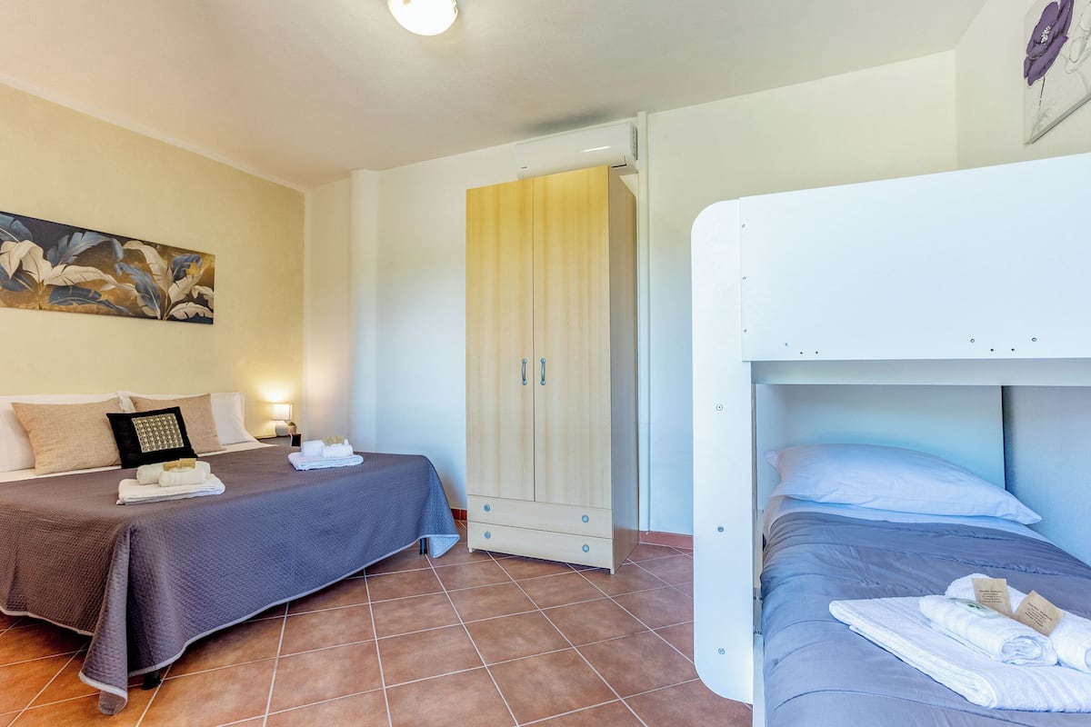 Habitació d'hotel amb dos llits, un armari, un quadre a la paret i un sòl de rajola.