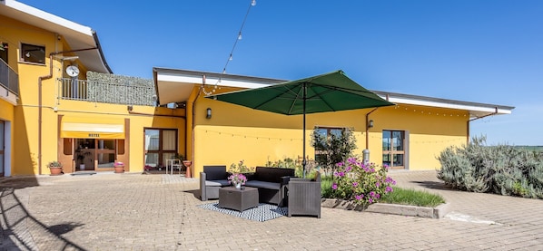 A yellow building with a 'HOTEL' sign, outdoor seating, and a green umbrella.
